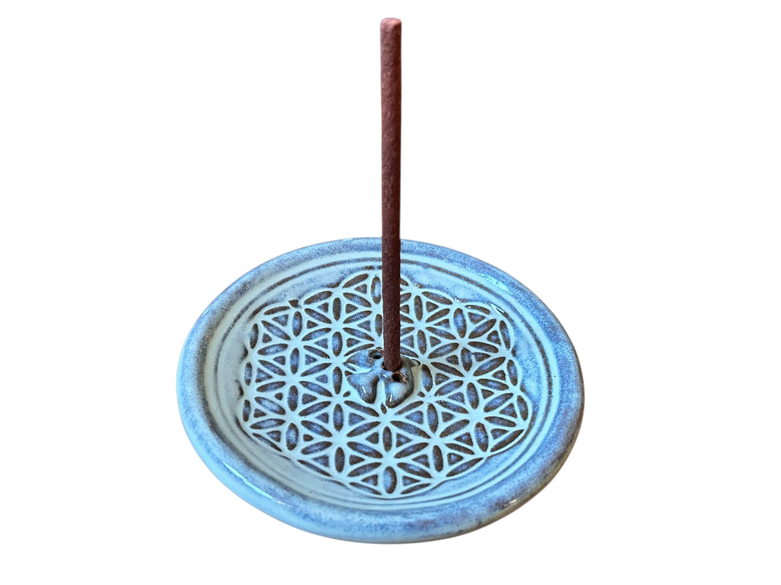 Ein Dhoop-Räucherstäbchen steht in einem hellblauen Keramikhalter mit Blume-des-Lebens-Muster